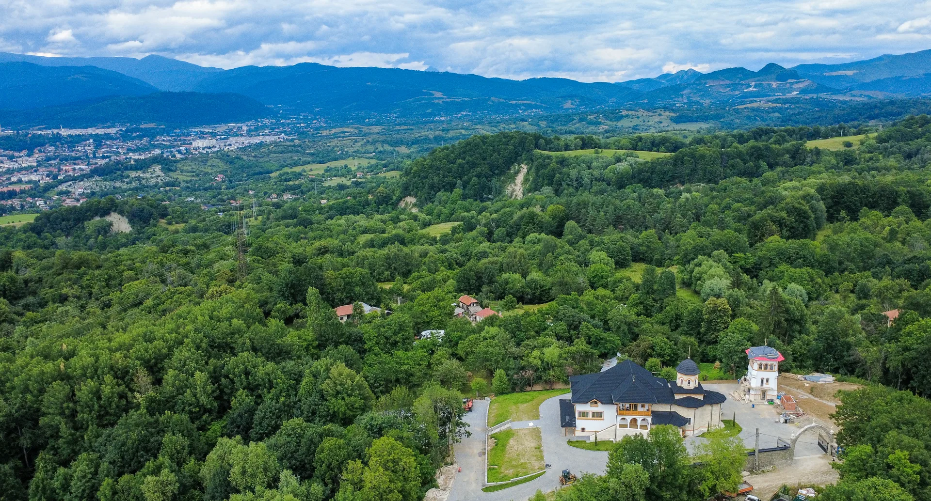 Vedere aeriană a schitului cu munții în fundal